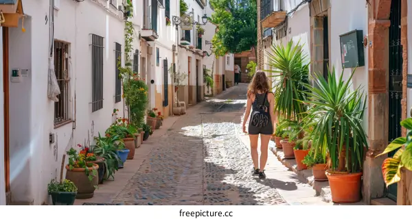A woman walking down a narrow street in a Spanish village