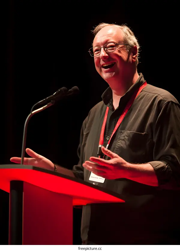 Man speaking at a conference with a microphone in his hand