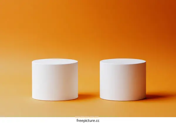 Two White Cylindrical Display Stands on Orange Background