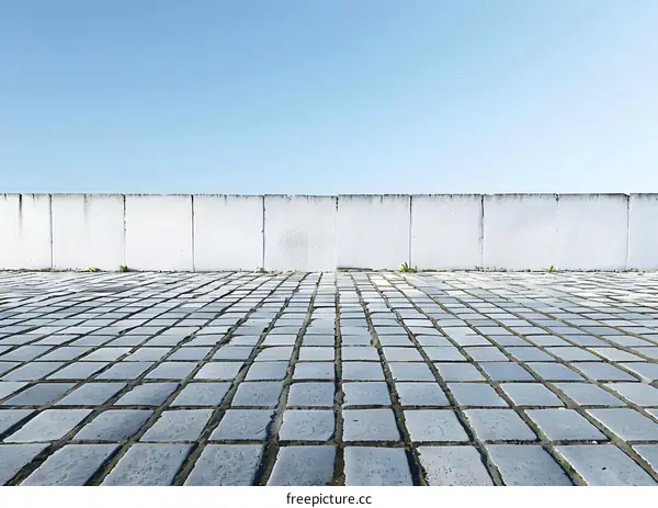 Empty Cobblestone Street with White Wall and Blue Sky