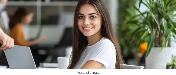 Smiling Woman Working on Laptop in Modern Office