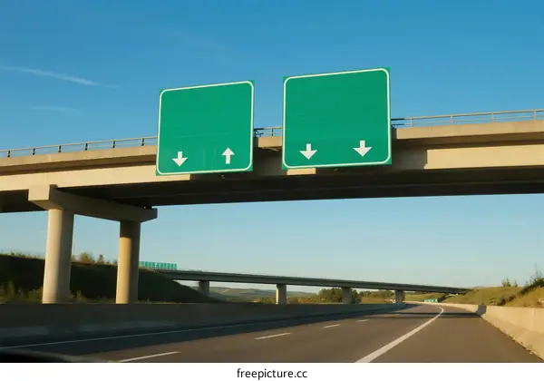 Two green road signs on an overpass with arrows indicating directions