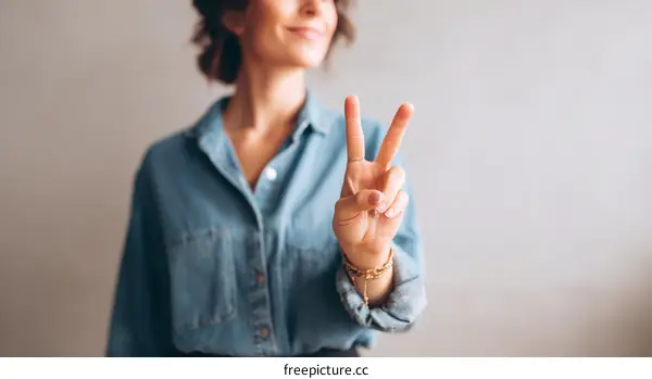 Woman Gesturing Peace Sign in Light Blue Shirt