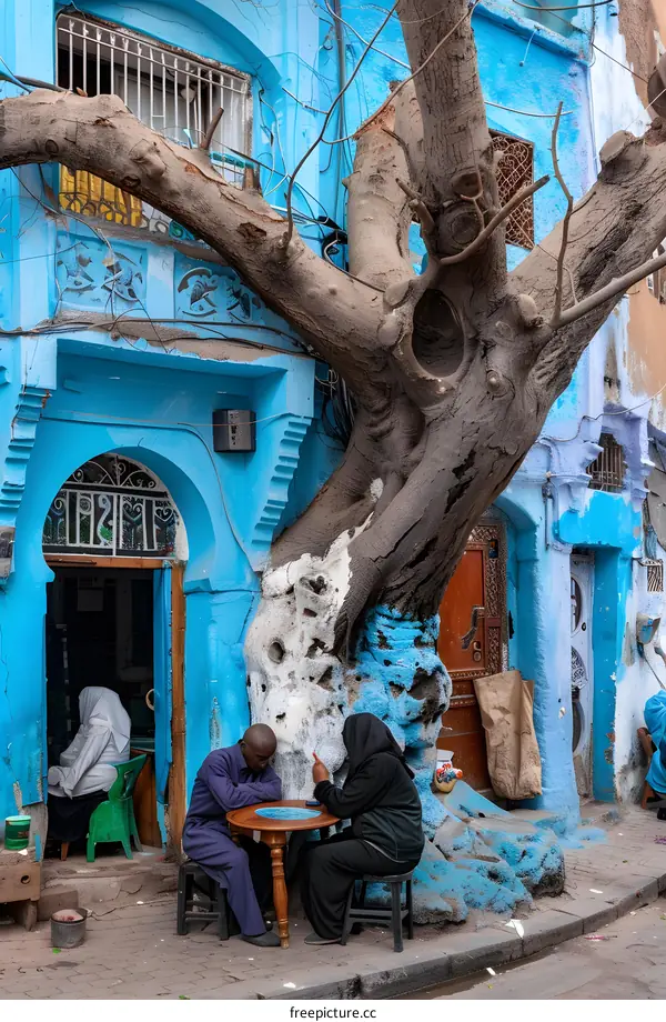 Blue Building with a Tree Growing Through it and People Sitting at a Table