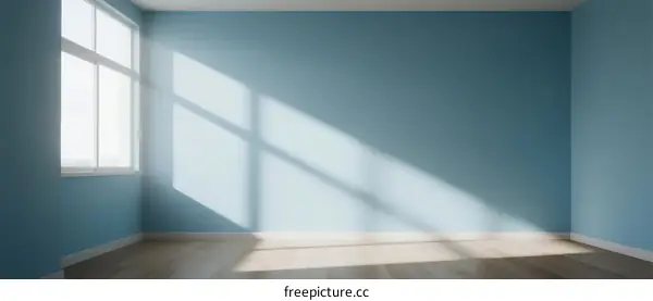 Empty room with blue wall and sunlight coming through window
