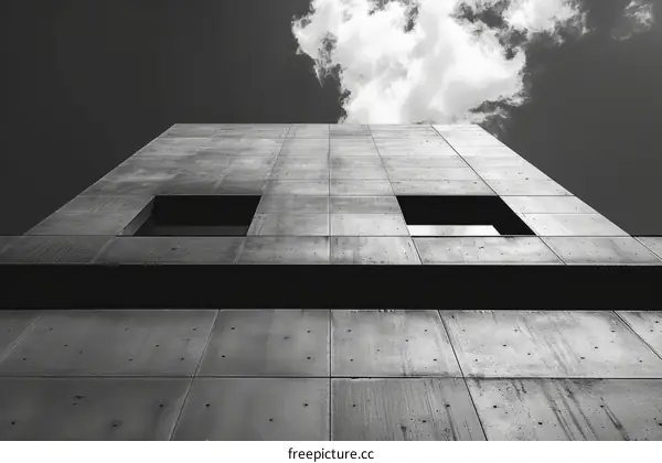 Black and white brutalist architecture with two square windows and a cloudy sky