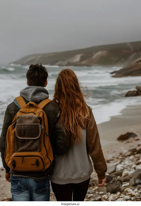Couple Walking On Beach With Backpacks