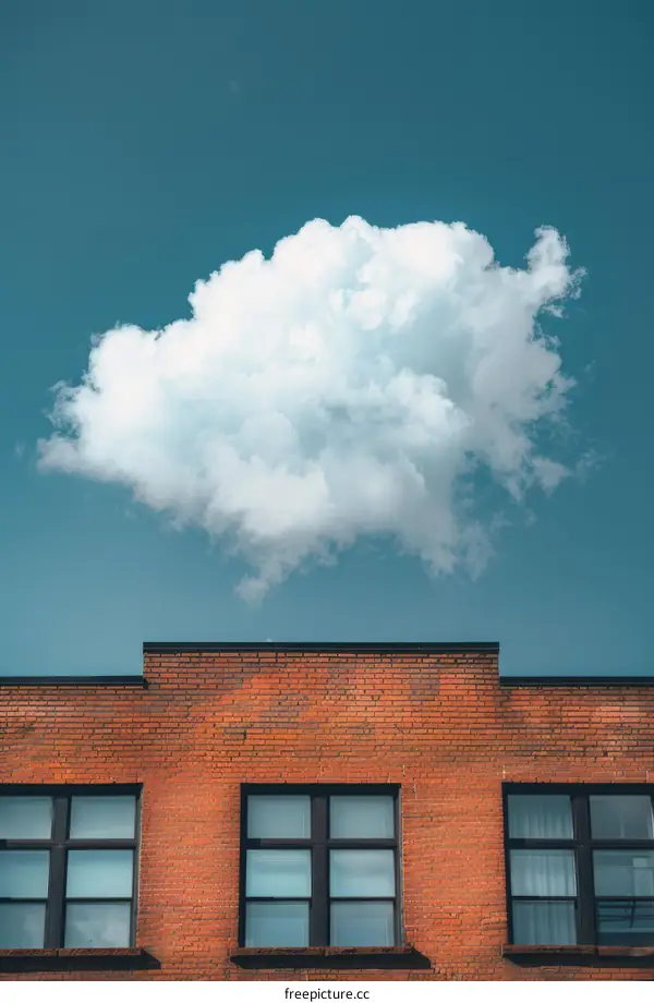 Large white cloud above a brick building with three windows