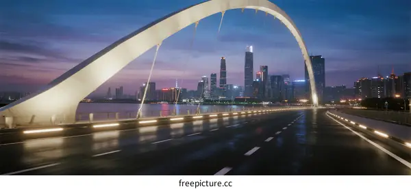 Modern arch bridge spanning over city at dusk with illuminated skyline