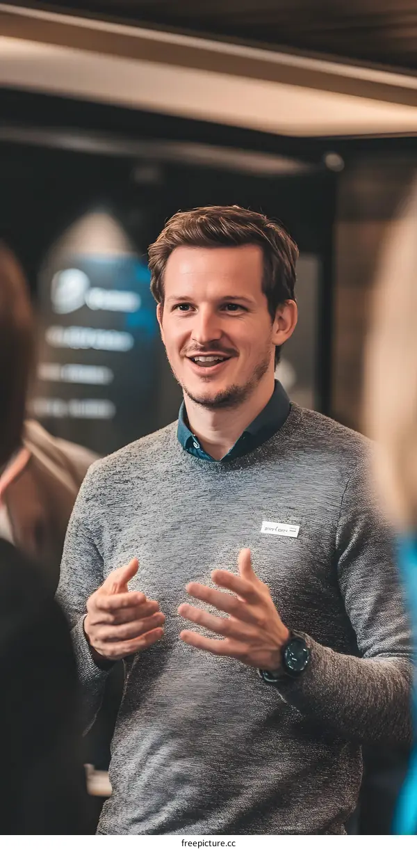 Smiling Caucasian Man with Grey Sweater Talking to Someone