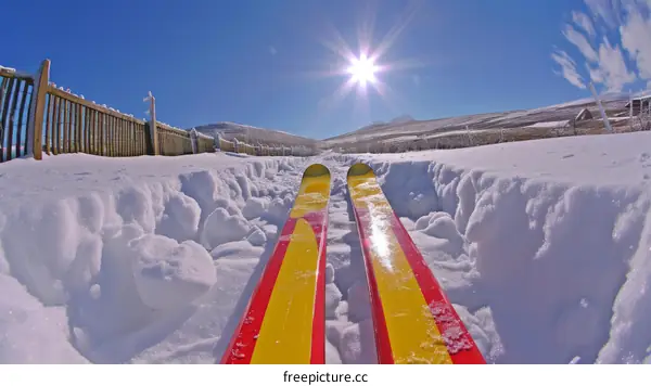 First-person view of skier with red and yellow skis on a snowy mountain