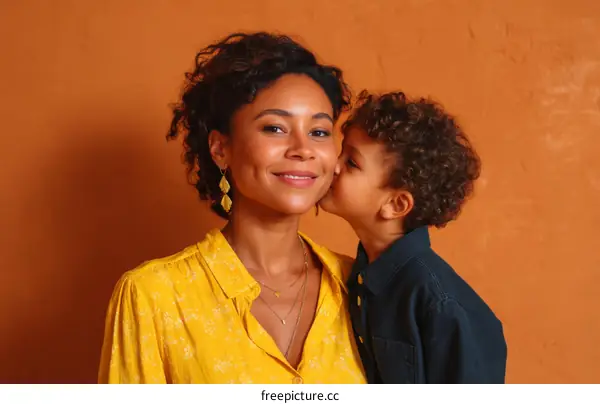 Mother and Son Affectionate Kissing against Orange Wall