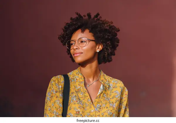 Young woman with curly hair wearing floral shirt and glasses