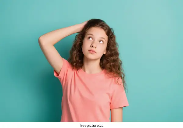Teenage girl with curly hair looking up with confused expression