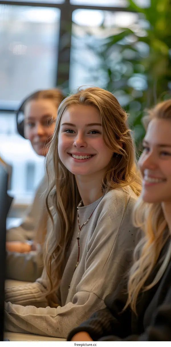 Three young women sitting in an office and smiling at the camera