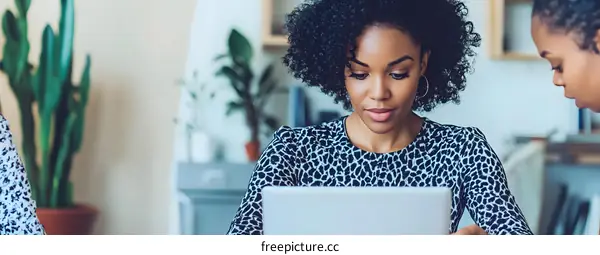 Two Black Women Using Laptop In Office