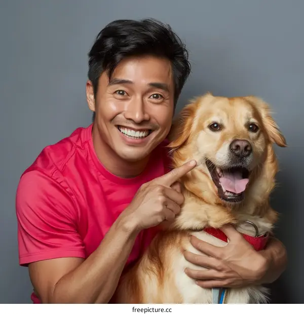 Asian man smiling and pointing at golden retriever dog