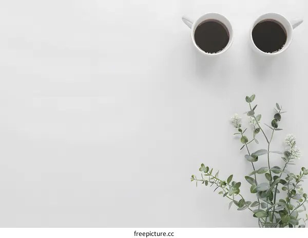 White Background With Two Cups of Coffee and Green Leaves