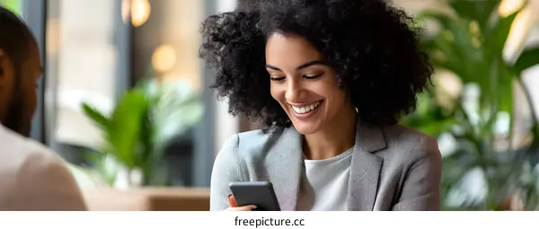 Smiling Black Woman Using Smartphone in Cafe