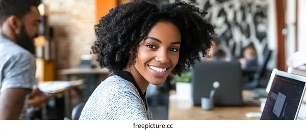 Smiling Black Woman Working on Laptop in Office