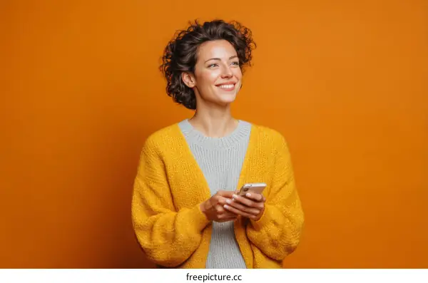 Smiling Woman Using Smartphone Against Orange Background