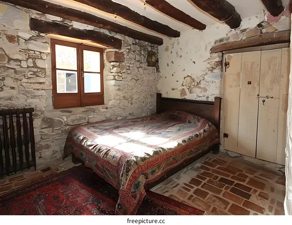 A cozy bedroom with a stone wall and a wooden beamed ceiling