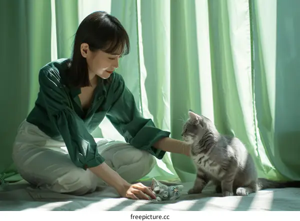 A woman is playing with a cat on the floor
