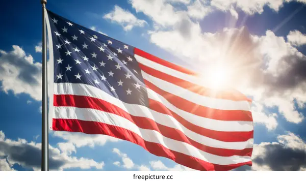 American flag waving in the wind with a bright sun behind it