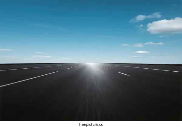 Endless road under clear blue sky with sunlight shining