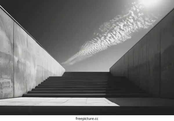 Black and white photo of a concrete staircase leading up to a bright sky