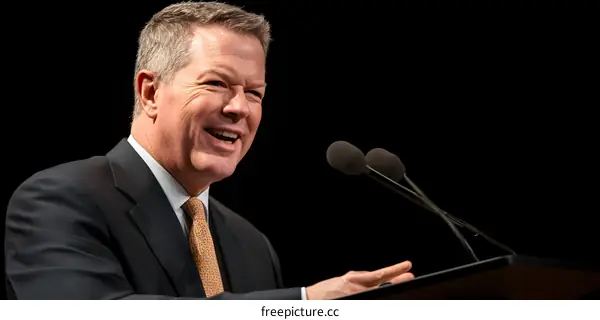 Man in Suit Speaking at a Microphone