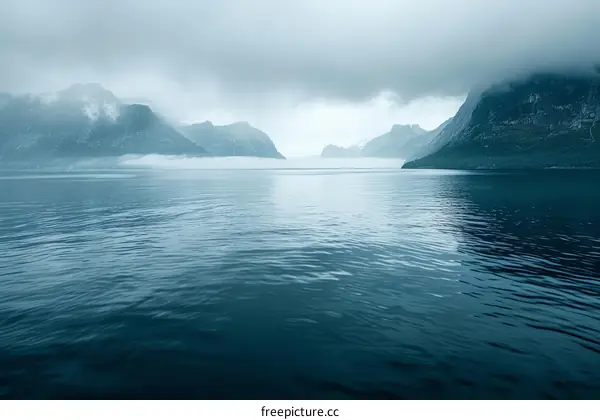 Misty fjord landscape with steep mountains and dark water