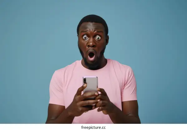 Shocked young black man looking at mobile phone screen
