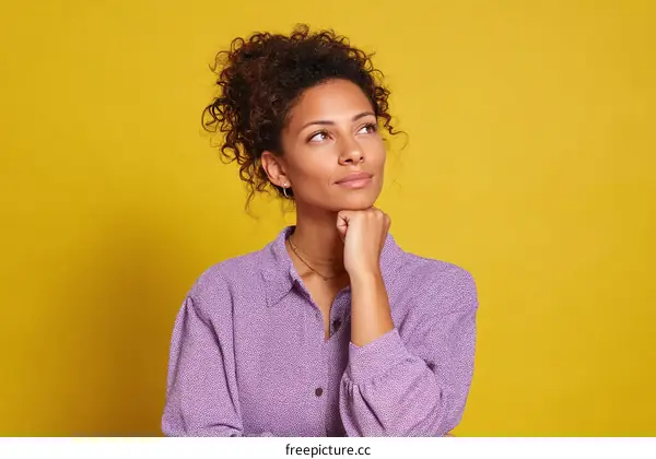 Thoughtful Woman in Purple Top Against Yellow Background
