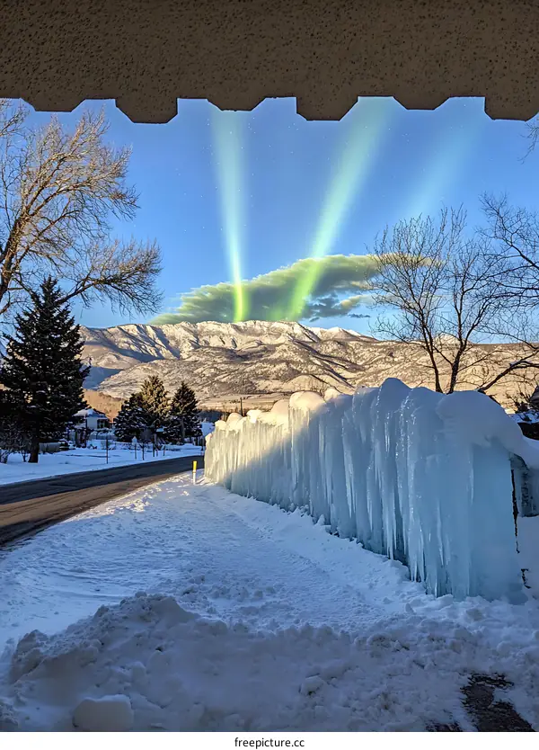 Green Light Show Over Snowy Mountain Range