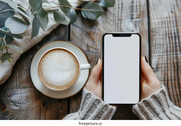 A woman in a gray sweater holding a white iPhone with a blank screen