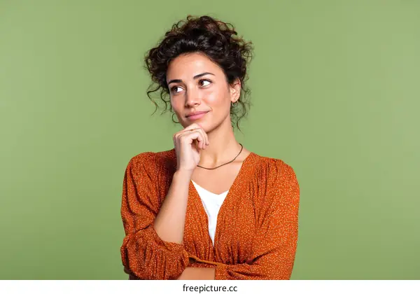 Thoughtful Woman in Orange Dress against Green Background