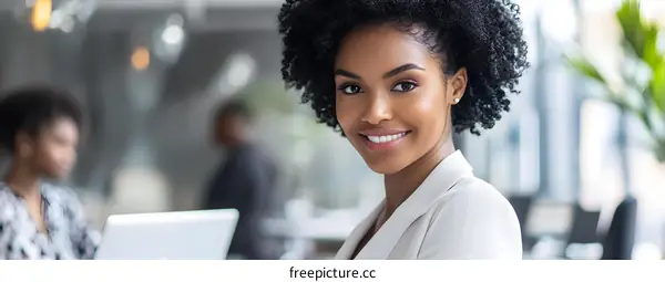 Smiling Black Woman in a White Blazer in an Office Setting
