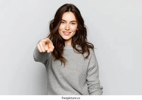 Woman Pointing Towards Viewer in Gray Sweater