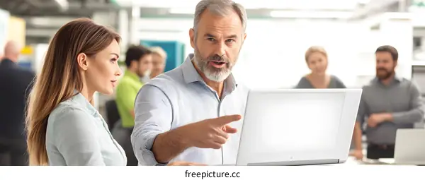 Businessman Discussing a Project With a Colleague Using a Laptop