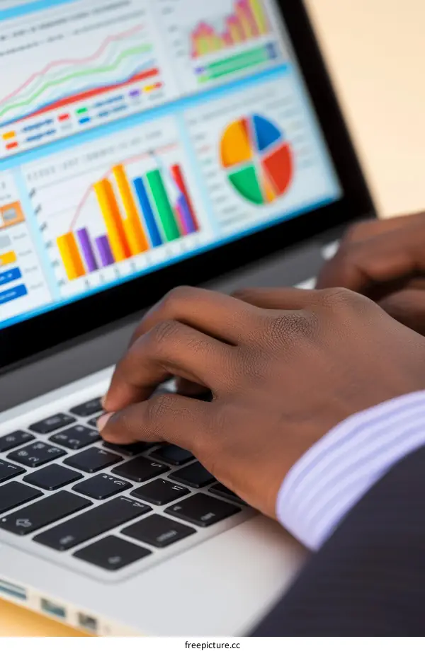 A business person of African descent is typing on a laptop.