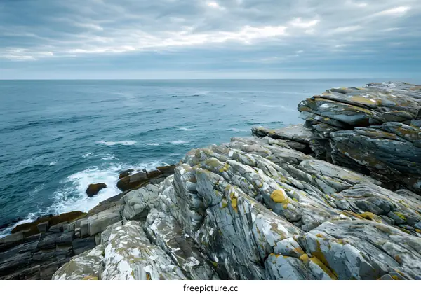 Rocky Coastline with Cloudy Sky and Blue Ocean