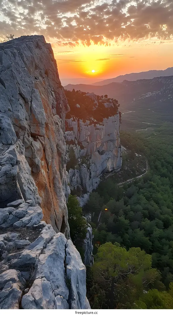 A beautiful landscape photo of a rocky cliff with a valley and mountains in the background