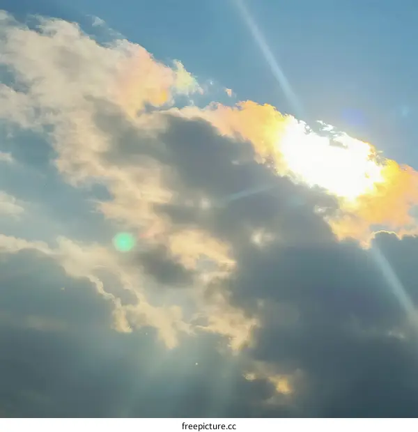 Sunlight Breaking Through Fluffy Clouds in Clear Sky