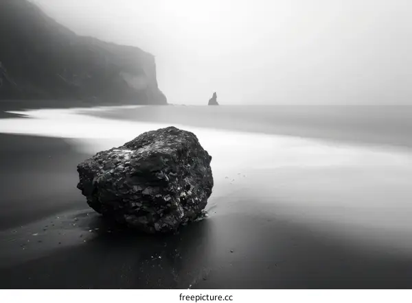 Monochrome Solitude: A Large Rock on a Foggy Beach