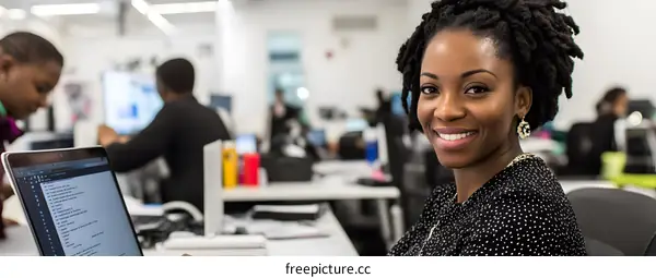 Smiling Black Woman Working At A Desk With Laptop