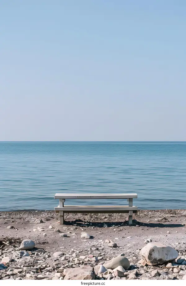 Lonely Bench on a Sandy Beach With Blue Water