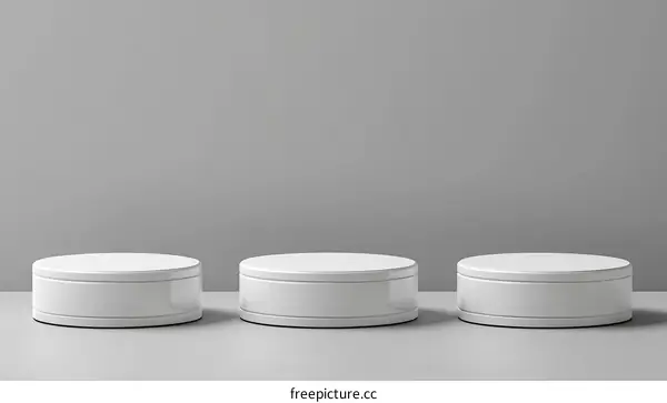 Three White Round Pedestals on Gray Background