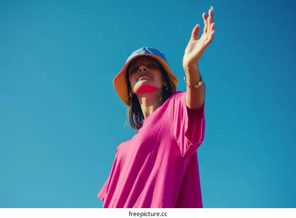 Woman in a bright pink shirt against a vibrant blue sky