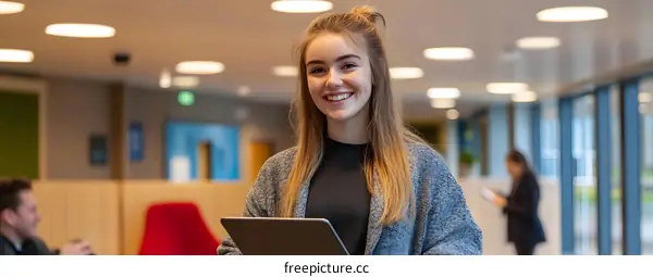 Smiling Young Woman Holding Tablet in Office Lobby